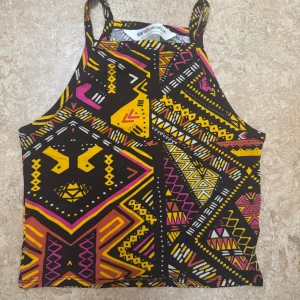 Färgglad mönstrad linne-topp H&M - Säljer en linne-topp från H&M med färgstarkt geometriskt mönster i svart, gul, rosa och orange. Storlek xs. Endast använd en gång. 