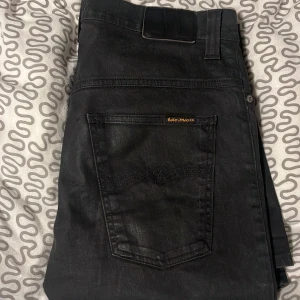 Nudie jeans svarta - Ett par nästan helt nya nudie jeans har bara haft på mig dem några gånger. Jeansen är W34 L34. Jeansen ser ut att vara väldigt glansiga men i verkligheten ser de inte ut så😁