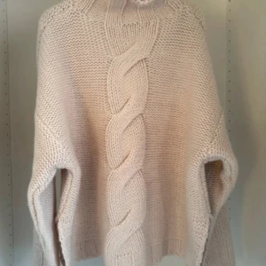 Beige stickad tröja med fläta från Zara  - Mysig beige stickad tröja med grov flätstickning framtill och hög hals. Tröjan har långärmade ärmar och en loose passform, perfekt för kyliga dagar. Den stickade strukturen ger en trendig och avslappnad look. Använd 3 gånger 