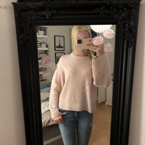 Ljusrosa stickad tröja Gina Tricot - Supermysig ljusrosa stickad tröja från Gina Tricot i ullblandning. Tröjan har rund hals, ribbade muddar och en loose passform som ger en chill vibe. Perfekt för att hålla sig varm under hösten och vintern. Passar dig som gillar enkel och söt stil.