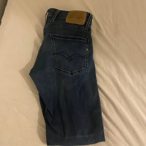 Replay anbass - Säljer ett par blåa jeans från Replay med klassisk femficksdesign och snygga detaljer på bakfickan. Jeansen har rak passform och är tillverkade i mjukt denimtyg som sitter skönt hela dagen. Perfekta för dig som gillar stilrena och tidlösa jeans.