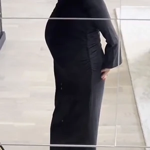 Svart tajt långkjol - Säljer en svart lång kjol med figurnära passform. Kjolen har snygga rynkade detaljer längs sidorna och är tillverkad i ett stretchigt material som sitter tight och markerar midjan. Perfekt för dig som gillar en stilren och elegant look.