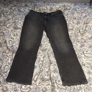 Svarta raka jeans - Säljer ett par svarta gant  jeans med raka ben och klassisk femficksdesign. Jeansen har en diskret tvättad look och är tillverkade i ett robust denimtyg. Passar dig som gillar en enkel och tidlös stil.