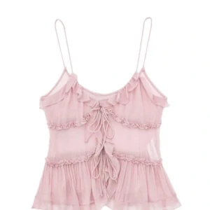 Rosa volangtop med snörning - (Reporna är på spegeln inte tröjan)💕Supersöt ljusrosa topp med tunna axelband, volangdetaljer och snörning framtill. Toppen är i ett tunt skönt matrial. Perfekt för dig som vill ha en topp som passar till alla tillfällen🌸Säljs inte längre🌸