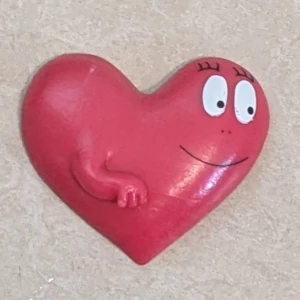 Barbapapa Hjärtformad Magnet - Söt hjärtformad magnet med Barbapapa-motiv. Röd färg, med ansikte och arm, perfekt för kylskåpet eller whiteboard. Små tecken på normalt slitage, men i gott skick. CE-märkt och tillverkad av plast. Samlarobjekt för Barbapapa-fans.
