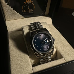 Seiko Deep Blue Mod Klocka - Säljer en stilren Seiko klocka med automatisk urverk, deep blue urtavla med arabiska siffror och datumvisning samt luminous handvisare. 39 mm klockan med ett klassiskt rundat silverfärgat boett och länkarmband i 904L stäl. Glas pa bada sidorna gjort av safir vilket innebär att den är reptälig. Perfekt accessoar för dig som gillar snygga detaljer och modern design.