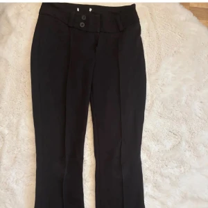 Svarta kostymbyxor med knappar - Stilrena svarta kostymbyxor med två knappar i midjan. 