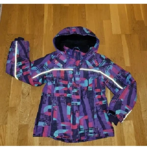 Jacka - Säljer en färgglad vinterjacka från Lindex med ett unikt mönster. Jackan har en huva och reflexdetaljer för extra synlighet. Perfekt för kalla dagar! Använd, men inga defekter. Tvättad!