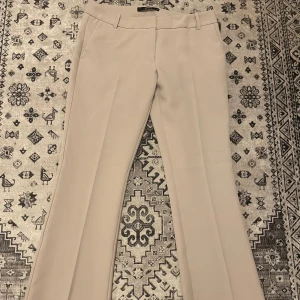 Beige petite bootcut kostymbyxor från BikBok - Snygga beige kostymbyxor från BikBok i bootcut-modell i storlek 38. Använd en gång och är i bra skick. 