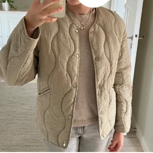  jacka från H&M  - Quiltad ljus grön jacka från H&M i storlek XS. Jackan har vågigt mönster, tryckknappar framtill och två snedställda fickor. Perfekt för lager-på-lager under höst och vår. LÅNADE BILDER. Aldrig använd som ny.