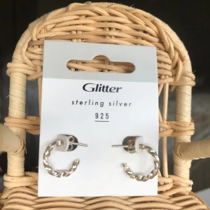 Glitter örhängen i sterling silver - Ett par snygga örhängen från Glitter i äkta sterling silver 925. De har en tvinnad design som reflekterar ljuset och ger fin glans. Perfekta att matcha med andra silversmycken för en stilren look. Ringen är ca 15mm stor