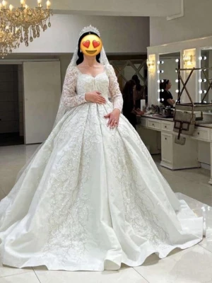 Vit glittrig bröllopsklänning med spets - Magisk långklänning i vitt med glittriga detaljer och broderad spets. Klänningen har långärmade spetsärmar, hjärtformad urringning och en stor, prinsesslik kjol. Perfekt för bal eller bröllop! Materialet är troligtvis polyester och spets. Storlek M/S