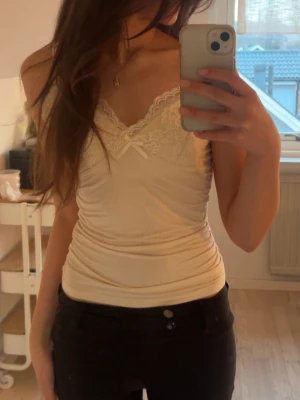 Ljusgul linnetopp med spets och rosett - Jag säljer denna ljusgula tröjan. Den har justerbara axelband och är jätte bra för sommaren 