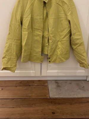 Gul bomberjacka från PTA - Fräsch gul bomberjacka från PTA med stilren design och coola detaljer som tryckknappar vid kragen och nederkanten. Jackan har lång ärm och är tillverkad i ett slätt syntetmaterial som känns lätt och bekvämt. Perfekt för dig som vill sticka ut med färg.