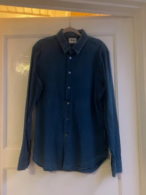 Blå skjorta från Acne Studios - Snygg blå skjorta från Acne Studios i storlek 52. Skjortan har klassisk krage, knappar hela vägen och lång ärm. Materialet är mjuk bomull som känns skönt mot huden. Perfekt för dig som gillar stilrena och enkla plagg med modern vibe.
