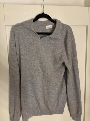 Grå stickad tröja från John Henric - Säljer en stilren grå stickad tröja från John Henric. Tröjan har en klassisk krage och är långärmad, perfekt för lager på lager under höst och vinter. Mjuk och skön kvalitet som passar till många olika looks.