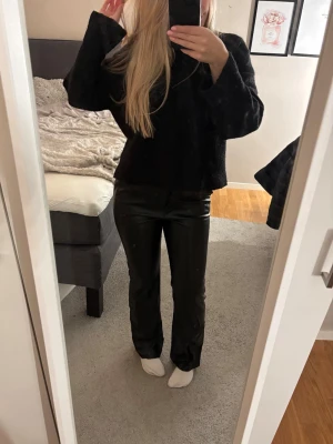 Svarta bootcut byxor i skinn  - Säljer ett par svarta bootcut-byxor från Madlady i skinn. Byxorna har normal passform och är i ett bra sick.