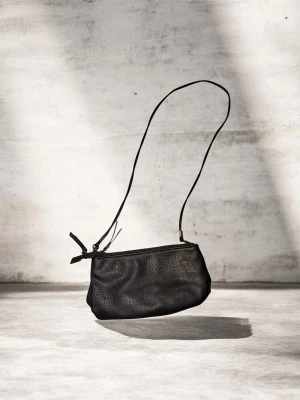 Svart axelväska från  Åhléns  - Säljer en stilren svart axelväska från ATP Atelier i mjukt skinn. Väskan har minimalistisk design med smal axelrem och dragkedja upptill. Perfekt storlek för det viktigaste och snygg att ha över axeln. Märkets logga finns på insidan.