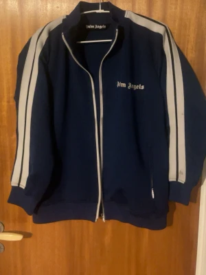 Blå Palm Angels hoodie med vita ränder - Säljer en snygg blå hoodie från Palm Angels säljer då jag inte använder den längre köpte utav en vän så vet inte riktigt om den e äkta så mitt pris är 800 men kan gå ner lite vid snabb affär 🙂