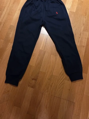 Svarta mjukisbyxor från Polo Ralph Lauren - Säljer ett par svarta mjukisbyxor från Polo Ralph Lauren med den klassiska röda loggan broderad på vänster sida. Byxorna har resår i midjan och vid bensluten samt sidofickor. Perfekta för chill eller träning.