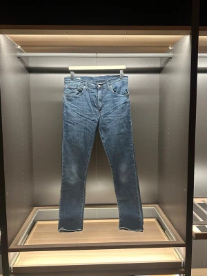 Levi's 512 mörkblå jeans W33 L34 - Snygga Levi's 512 jeans i mörkblå tvätt med klassisk femficksdesign och smal passform. Jeansen har normal midja och raka ben med lätt stretch för extra komfort. Perfekt för dig som gillar en stilren och modern look. Det är bara att skriva vid frågor eller andra funderingar