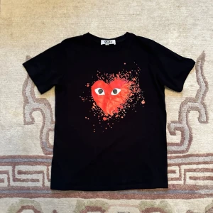 CDG PLAY  - Svart t-shirt från Comme des garcon PLAY med ett stort rött hjärta med ögon på bröstet och coolt splattermönster runtom. Klassisk rund hals och korta ärmar. Materialet känns som mjuk bomull, perfekt för chill dagar. Är i storlek S men skulle säga att den passar xs med!☺️