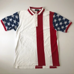 Y2k USA piké M - Unik skjorta från Catalina Bay i storlek M med amerikanskt flaggmönster. Röd och vit randig front och rygg, blå korta ärmar med vita stjärnor. Krage med röda och vita ränder, knappar framtill. Tillverkad i 100% bomull, perfekt för dig som gillar statement-plagg. Riktig fet y2k. Archive