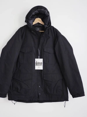 Svart parkajacka Uniqlo x Engineered Garments - Säljer en svart, varm och funktionell jacka med flera fickor och huva. Del av limiterad collab mellan Uniqlo och Engineered Garments. Köpt ny för ca 4 500 kr. Inte använd och tidlös design. Jackan är medium i storlek har fyra stora fickor framtill, huva och dragsko i nederkant. Tillverkad i slitstark bomull och polyesterblandning, perfekt för kyliga dagar. Stängs med dragkedja och tryckknappar. 