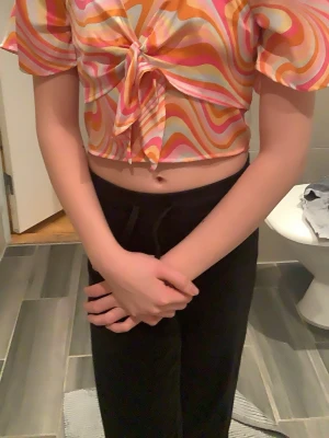 Färgglad omlottopp från Lindex - Säljer en superfin croppad omlottopp från Lindex shoppad i storlek 134/140. Toppen har ett färgstarkt psykedeliskt mönster i orange, rosa, vitt och gult, med knyt framtill och korta, vida ärmar. Perfekt för dig som gillar statement-plagg!