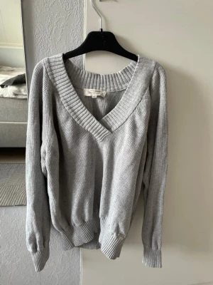 Grå ribbad tröja från Flash Woman - Säljer nu grå ribbad tröja från Flash Woman. Tröjan har bred v-ringning, långa ärmar och breda muddar vid ärmslut och nederkant. Perfekt för dig som gillar en enkel men snygg look❣️