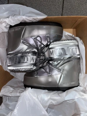 Moon boots icon low glance storlek 36-38 - Säljer ett par Moon Boot Icon Low i snygg silverfärg. Helt nya bara testas inomhus och allt originalt medföljer. Kan mötas i Stockholm eller frakt. Storlek 36-38