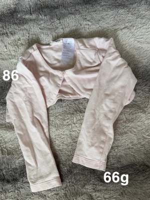 Ljusrosa bolero-kofta från Kappahl  - Supersöt ljusrosa bolero-kofta från Kappahl. Koftan har lång ärm, rund halsringning och en knapp framtill. Perfekt att slänga över en klänning eller topp för extra värme under vår och sommar.🌸 Fint använt skick. Storlek 86.