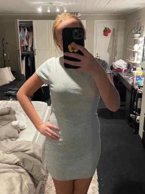 Grå ribbad kortklänning från Pieces - Säljer en enkel och stilren grå ribbad kortklänning från Pieces. Klänningen har rund halsringning, korta ärmar och en tight passform som framhäver figuren. Perfekt att styla med sneakers eller boots för en cool look.