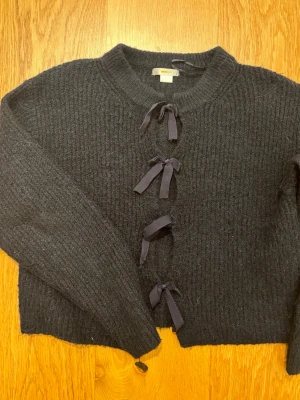  Marin blå stickad kofta med rosetter från Gina Tricot - Mysig marin blå stickad kofta från Gina Tricot Young i storlek 146/152. Långärmad och i mjukt material.