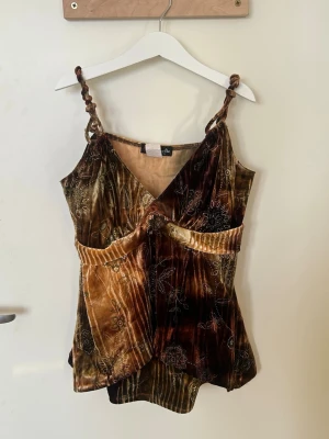 Brun blommig linnetopp - Unik brun och beige linnetopp i sammet med blommigt mönster och broderade detaljer. Toppen har omlott-look, twistade axelband och v-ringning. Storlek S 💕