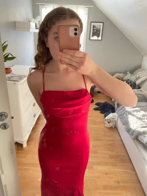 Röd långklänning med öppen rygg - Säljer en snygg röd långklänning med tunna axelband som är justerbara. Klänningen har öppen rygg med diskret dragkedja baktill. Endast använd en gång. 