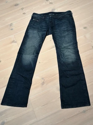 Diesel zatiny jeans  - Säljer ett par diesel zatiny jeans i mörkblå tvätt med klassisk bootcut-passform. Jeansen har fem fickor, knapp och dragkedja fram samt diesel patch bak i midjan. Materialet är slitstarkt denim och byxorna har en snygg faded effekt på låren.