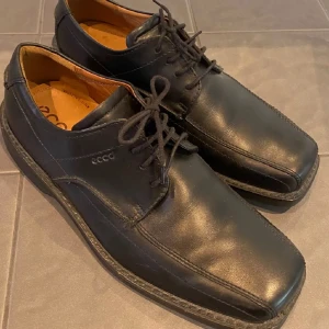 Svarta skinnskor från Ecco - Snygga svarta skinnskor från Ecco med snörning och fyrkantig tå. Perfekta för en stilren look. Skorna har en robust sula som ger bra grepp. Endast använda 2 gånger. Nypris c:a 1500 kr, nu endast 200❤️hör av dig vid frågor! Priset kan diskuteras.