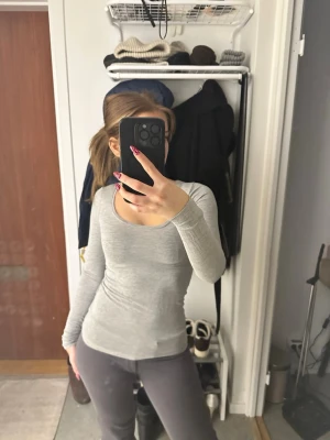 Ljusgrå långärmad topp - Säljer en ljusgrå långärmad topp med rund halsringning. Toppen är tight i passformen och tillverkad i ett mjukt och stretchigt material, perfekt att styla till jeans eller mjukisbyxor. Enkel och stilren design som funkar till många olika looks.