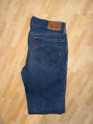 Levi's 710 mörkblå jeans - Snygga Levi's 570 jeans i mörkblå tvätt med klassisk femficksdesign och röd Levi's-tag på bakfickan. Modellen är slim och har raka ben med normal passform. Jeansen är tillverkade i slitstarkt bomullsmaterial och har en klassisk knappgylf.