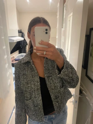 Svartvit rutig overshirt med krage - Säljer en svartvit rutig overshirt med klassisk krage och knappar framtill. Jackan är croppad och har en loose fit, perfekt att slänga över en t-shirt eller hoodie. Materialet känns mjukt och lite tjockare, vilket gör den extra skön under kyligare dagar.