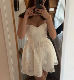 Studentklänning från showpo - Supersöt vit kort klänning med blommigt mönster och justerbara axelband. Klänningen är i väldigt fint skick och har en dragkedja på baksidan. Den är från showpo, orginalpris ca 900kr. Perfekt för student eller sommarens alla tillfällen!