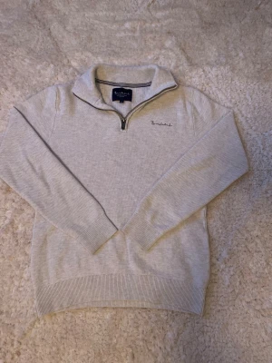 Ljusgrå/vit stickad tröja från Bondelid - Snygg stickad tröja från Bondelid i storlek S. Tröjan har en klassisk half zip-dragkedja vid kragen och diskret broderad logga på bröstet. Ribbstickade muddar vid ärmslut och nederkant ger en clean look. Perfekt för chill höst- och vinterdagar. Hör av dig vid frågor👌
