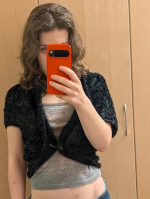 Svart fluffig kofta från Miss Sixty - Unik svart kofta från Miss Sixty i storlek M, tillverkad i Italien. Koftan har en fluffig och glansig yta med en cool asymmetrisk form som ger en edgy vibe. Materialet är en mix av polyamid och angora, vilket gör den supermjuk och skön. Perfekt för dig som gillar statement-plagg.