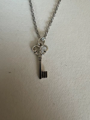 Silverhalsband mindre nyckel - Perfekta julklappen 🌲  Säljer smycken som skapats som hobby av mig och dottern.   Halskedjor är 50cm.  Bilder på berlock kan vara missvisande så är det viktigt så fråga gärna om mått 🌹  Smycken är inte av äkta guld/silver .   Inga bud godtas då priserna är så billiga❤️
