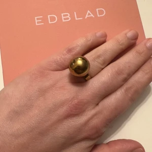 Edblad Statementring - Cool ring från Edblad i guldig metall med en stor, rund kula som blickfång. Ringen har en enkel, modern design som verkligen sticker ut och passar perfekt för dig som gillar att göra ett statement med dina accessoarer.