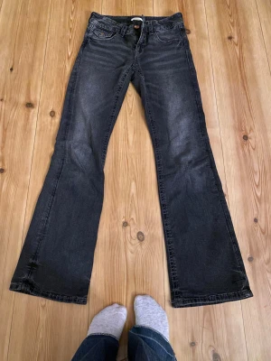 Lågmidjade bootcut jeans - Snygga jeans från Gina Tricot i storlek 164. Bootcut-modell med coola broderade detaljer på bakfickorna och kopparfärgade knappar. Jeansen har klassisk femficksdesign och är tillverkade i mjukt denimtyg med lätt tvättad look.