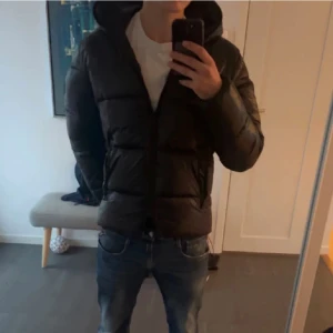 Svart  Save The Duck jacka - Säljer en svart pufferjacka från Save The Duck med huva och dragkedja. Jackan är 100% animal free och har en snygg, quiltad design. Perfekt för dig som vill ha en varm och schysst jacka. Skriv vid funderingar och kom med bud 