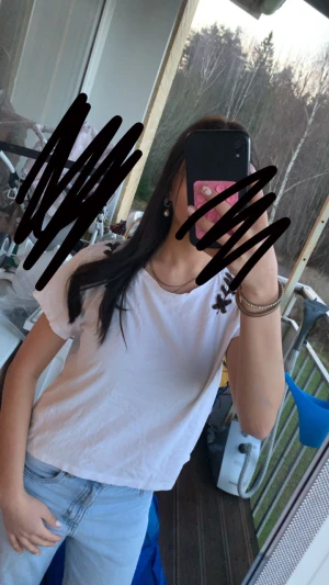 Vit t-shirt med snörning vid axlarna - Säljer en vit t-shirt med korta ärmar och cool snörningsdetalj i svart vid båda axlarna. Rund halsringning och loose passform, perfekt för en chill och avslappnad stil. Materialet känns som bomull och toppen är enkel att matcha med jeans eller shorts.