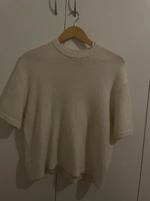 Beige stickad tröja Gina Tricot S - Mysig stickad tröja från Gina Tricot i beige färg. Modellen har korta ärmar, rund hals och ribbade detaljer vid hals, ärmslut och nederkant. Perfekt för dig som gillar enkel och clean stil med en soft vibe.